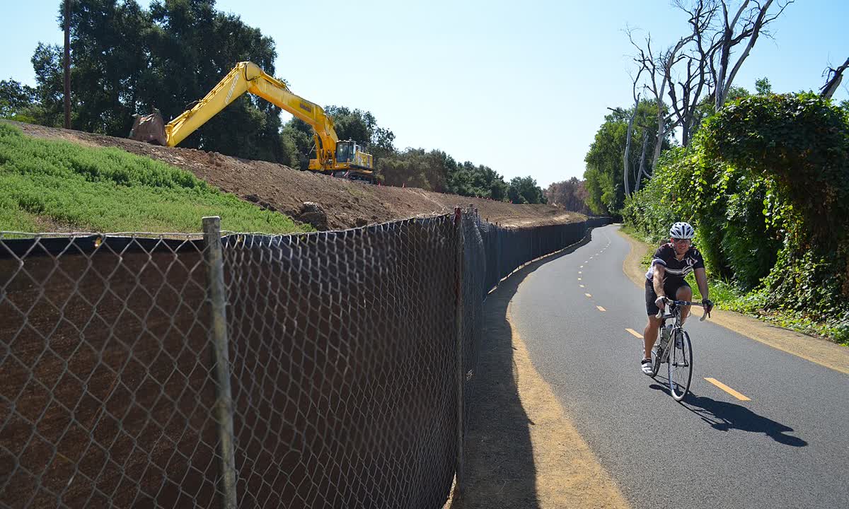 Excavator working on a levee slope next to a bike path in north Sacramento